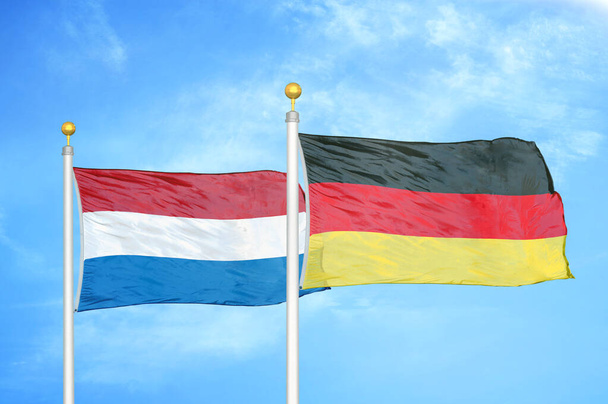 Holandia i Niemcy dwie flagi na maszcie flagowym i niebieskie zachmurzone tło nieba - Zdjęcie, obraz