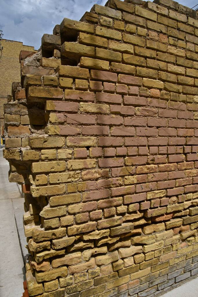 Eine alte Mauer eines Backsteingebäudes dient als Trennwand zu einem privaten Parkplatz  - Foto, Bild