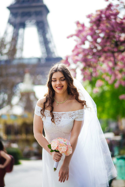 Beautiful bride in rich wedding dress whirls on the square before the Eiffel Tower - Foto, Imagen