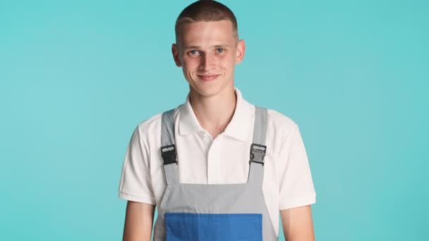 Young attractive cheerful builder in uniform happily smiling on camera over colorful background - Video, Çekim