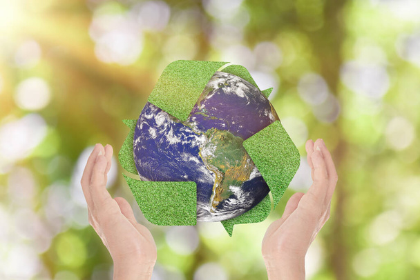 Zöld fű újrahasznosítani szimbólum és a Föld kezében zöld természet háttér. Környezetvédelmi koncepció. A kép elemeit a NASA bocsátotta rendelkezésre - Fotó, kép