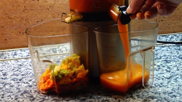 El jugo de fruta fresca que cae en la lata de plástico durante el proceso de hacer jugo de fruta prensado en frío en el fabricante de jugo. - Imágenes, Vídeo