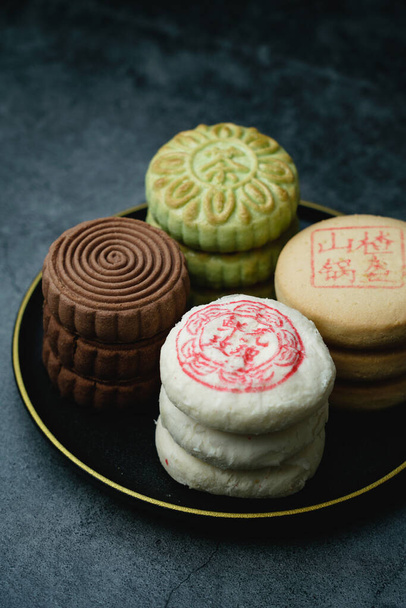 Delicious traditional Chinese pastry on a dark background. Chinese translation on pastry:Rose Cake with flowers, Hawthorn cake, Green tea crisp - Foto, afbeelding