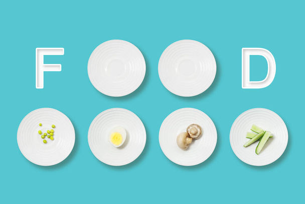 Healthy food minimalist flat lay. Food inscription and white plates with mushrooms, egg, peas and cucumbers on a blue background. - Foto, Bild