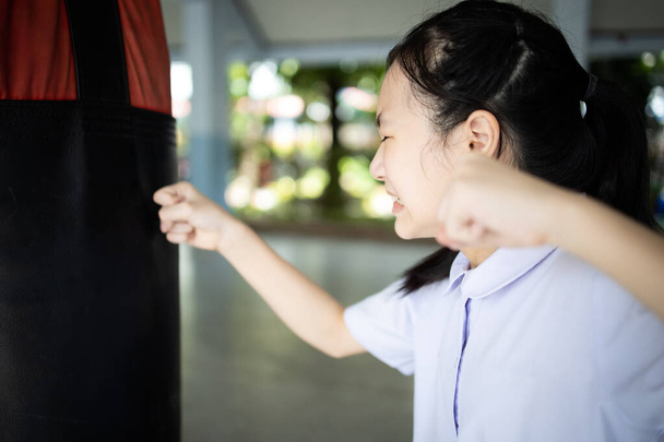 Asijská studentka pláče a zvedá pěsti, ženy se mlátí do boxovací pytel vyndá svůj vztek, emocionální výbuch, stres úlevu, cítí naštvaný, zklamaný, sebenenávist, katarze koncept - Fotografie, Obrázek
