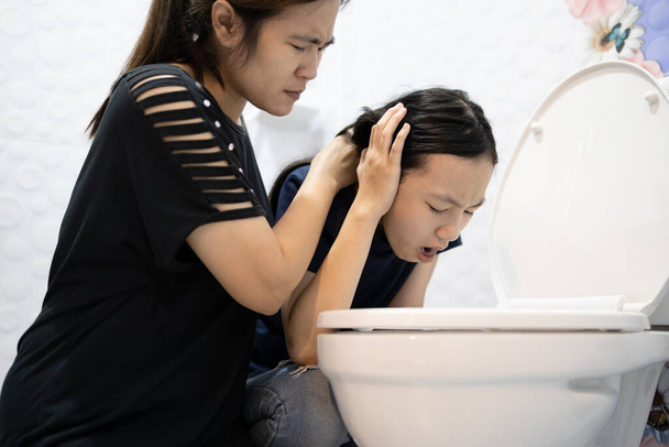 Enfant asiatique malade sur le point de vomir, vomir, vomir dans le bol des toilettes, la mère prend soin d'elle de près, souffrant d'indigestion, d'intoxication alimentaire, de maladies infectieuses aiguës, de gastrite proble - Photo, image