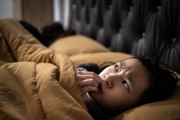 Испуганный азиатский ребенок девочка смотрит вокруг и ногтей укуса, стресс, беспокойство, чувствует себя напуганным, тревога, слыша что-то навязчивое, симптомы неврологических, галлюцинаций, недостаточно отдыха, Шизофрения концепции - Фото, изображение