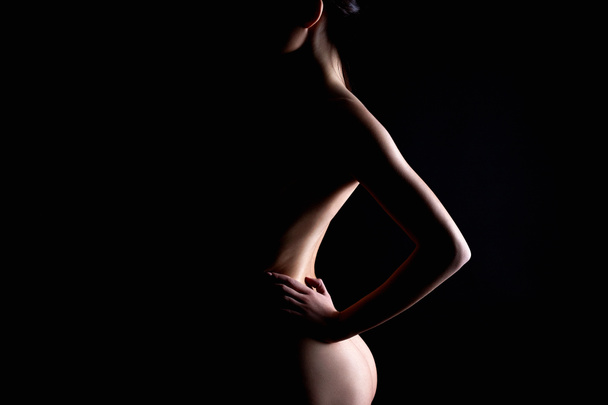 暗闇の中でヌード女性のシルエット。美しい裸のボディガール。ブーティーと戻る - 写真・画像