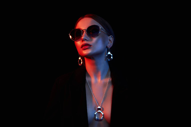 beauty young woman in colorful bright lights. Fashion beautiful girl in sunglasses and jewelry - 写真・画像
