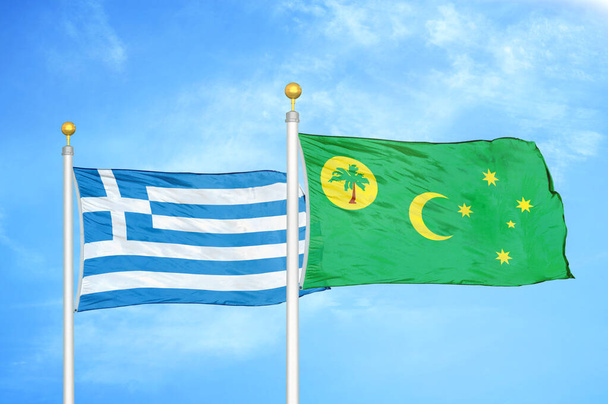 Kreikka ja Kookossaaret Keeling kaksi lippua lipputangot ja sininen pilvinen taivas tausta - Valokuva, kuva