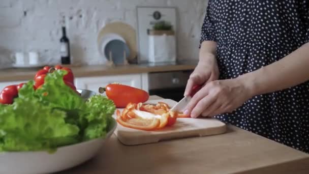 Krásná mladá žena v domácnosti drží nůž řezy pepř salát vaření zelenina misky. - Záběry, video
