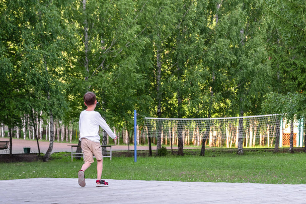 The boy runs in the park. child on stage. basketball net in the park - Фото, изображение