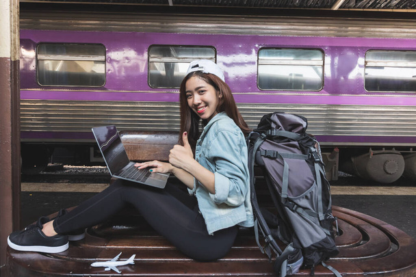 Приваблива молода азійка з рюкзаком для подорожей за допомогою комп'ютерного ноутбука. Концепція мандрівного життя. - Фото, зображення