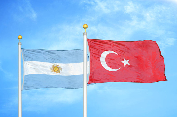 Argentinië en Turkije twee vlaggen op vlaggenmasten en blauwe bewolkte lucht achtergrond - Foto, afbeelding