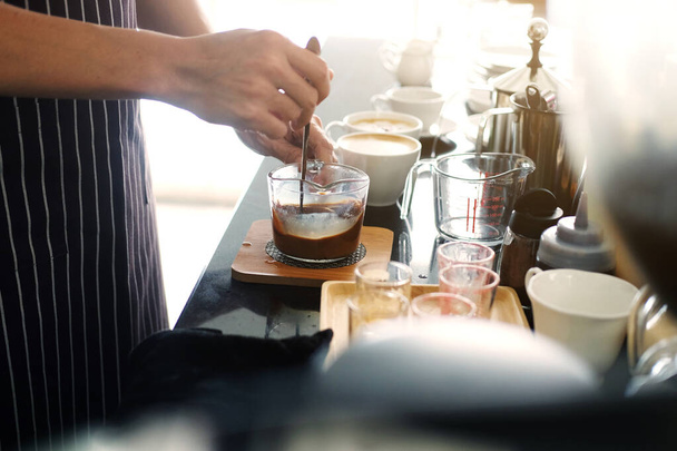 Azji barista młody człowiek robi kawę według zamówienia w barze counter z naturalnym słońcem w godzinach porannych w nowoczesnej kawiarni i restauracji. - Zdjęcie, obraz