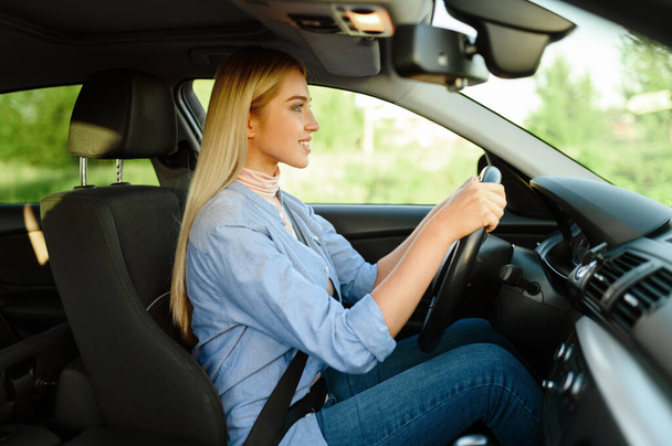 Fröhliche Studentin im Auto, Fahrschulstunde. Mann bringt Frau das Autofahren bei. Führerscheinerziehung - Foto, Bild