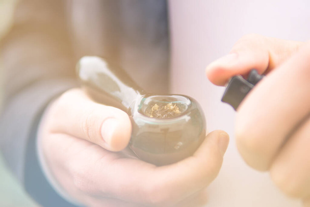 Smoking pipe in hand. Sativa THC CBD. Indica medical health. The pot leaves on buds. Cannabis nature bud. Marijuana weed bud and grinder. - Photo, Image