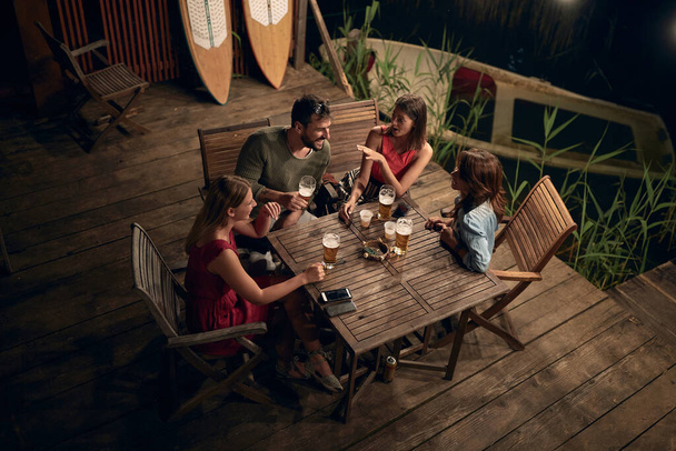 Mensen praten en drinken bier en genieten van een mooie avond - Foto, afbeelding