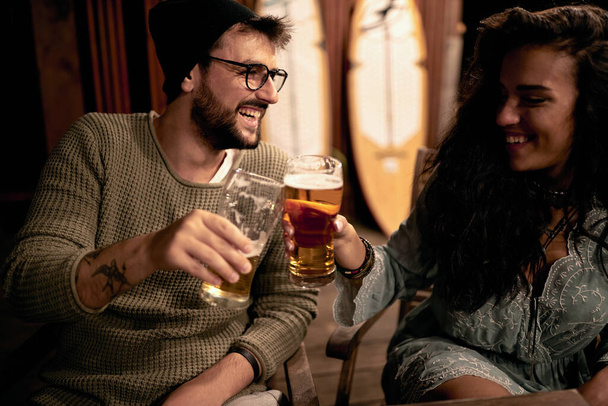Smiling man and woman enjoying at evening fun and drinks beer together .Couple enjoying drinks together. - Fotó, kép