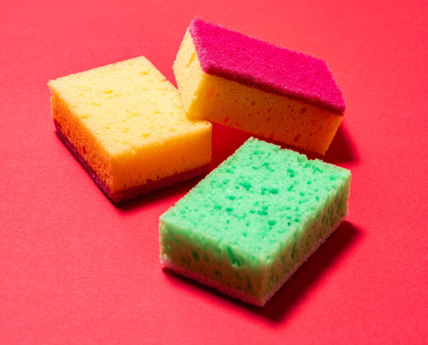 Multicolored sponges for washing dishes on a red background - Photo, Image