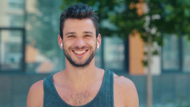Young man exercising outside. Slow motion video portrait of guy with cheerful positive and good smile. Looking straight with positive sight. Sportsman on video. - Footage, Video