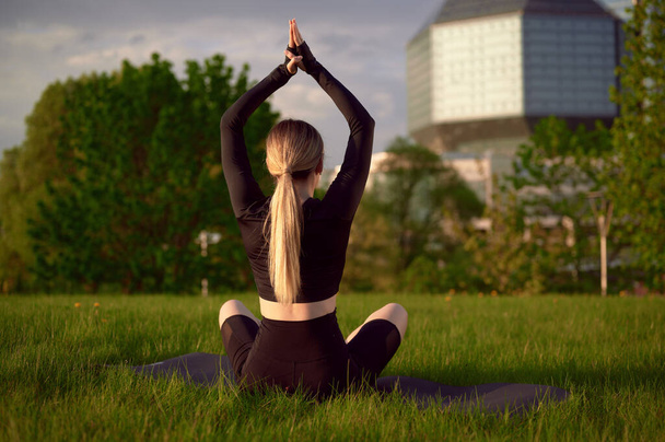 Mujer meditando relajándose en lotos yoga posan en auriculares y escuchando música. Chica haciendo yoga sentado en posición lotos en el parque - Foto, imagen