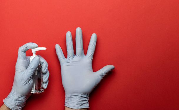 Fond médical rouge. Gel nettoyant antibactérien médical et gants de laboratoire sur fond d'équipement de protection contre le virus. Désinfectant clair dans une bouteille de pompe. Nouveau Coronavirus 2019-nCoV. - Photo, image