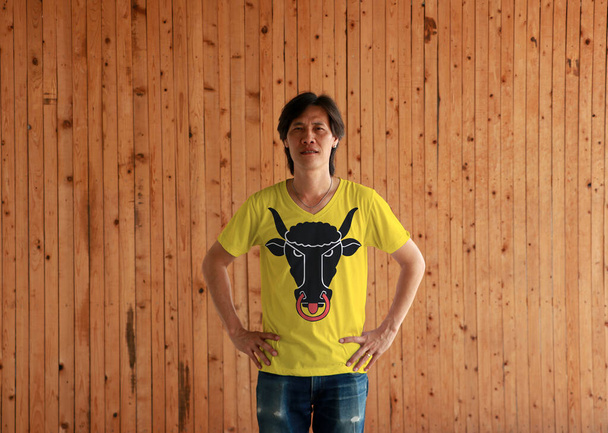 Man wearing Uri flag color shirt and standing with akimbo on the wooden wall background. The canton of Switzerland. - Photo, Image