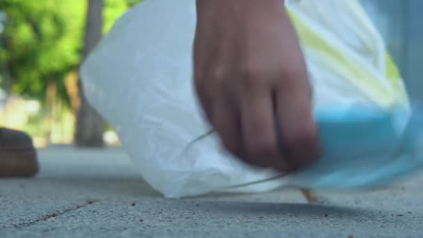 Nahaufnahme einer schützenden Gesichtsmaske auf dem Boden und eines Mädchens, das sie aufhebt - Filmmaterial, Video