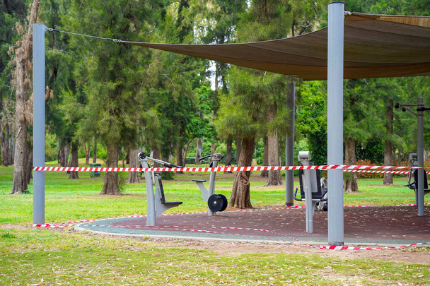 Sportplatz im Park mit rot-weißem Band. Geschlossener Spielplatz während einer Pandemie. Covid-19-Pandemie, leere Spielplätze, rotes verbotenes Klebeband - Foto, Bild
