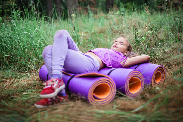 Week-end actif et sain. Enfant heureux se reposer et s'amuser sur le tapis de yoga violet pendant leur randonnée dans la forêt, Voyage local. Rester dans une nouvelle vie normale. Style de vie extérieur été - Photo, image