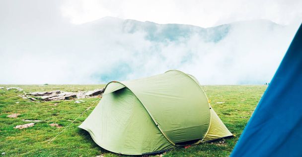 Des tentes dans le désert. Tentes dans un pré herbeux avec brouillard sur la montagne. Trekking, camping, randonnée et concept de vie sauvage. Véritable aventure extérieure. - Photo, image