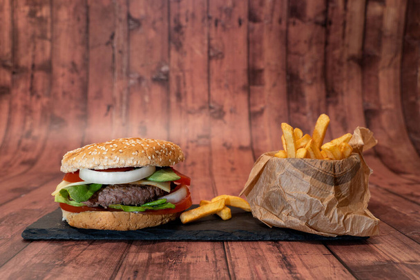 Handgemachter Burger mit Pommes auf Holzgrund - Foto, Bild