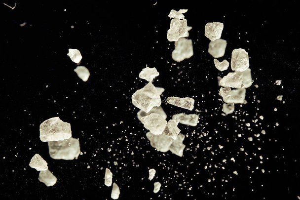 Closeup de cristais de sal parecia asteróides na escuridão do espaço aberto colorido em amarelo
 - Foto, Imagem