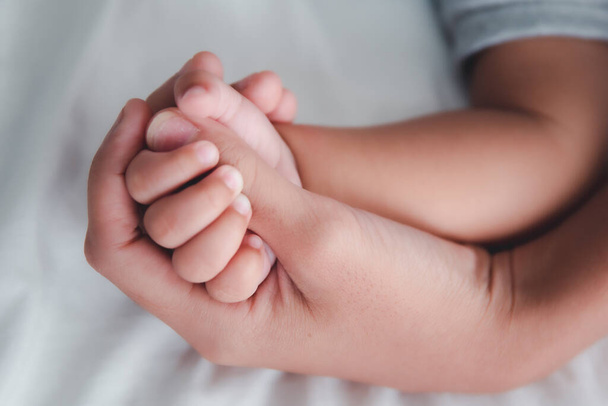 Fechar Mão de bebê adormecido na mão da mãe
. - Foto, Imagem