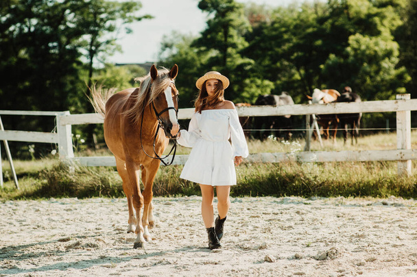 Bella ragazza hippie con cavallo su uno sfondo ranch, vista frontale. La ragazza col cappello. - Foto, immagini