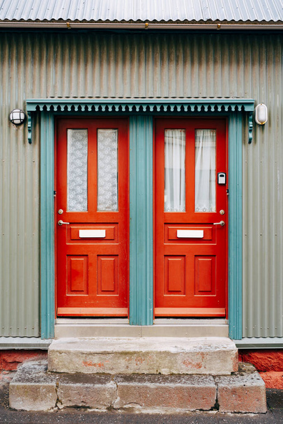 Dvě oranžové vstupní dveře se sklem a závěsy v modrých dveřích. - Fotografie, Obrázek
