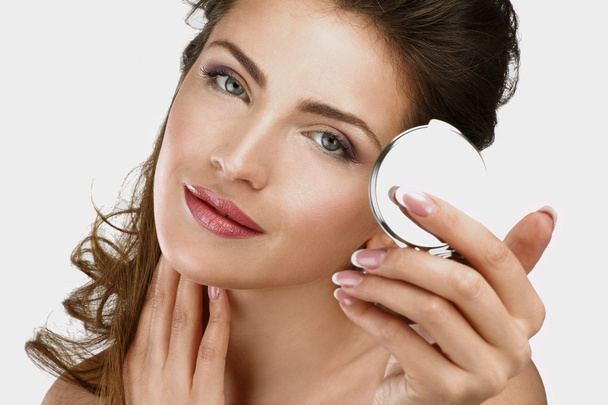 Closeup of a beautiful woman checking her makeup in the mirror - Foto, imagen