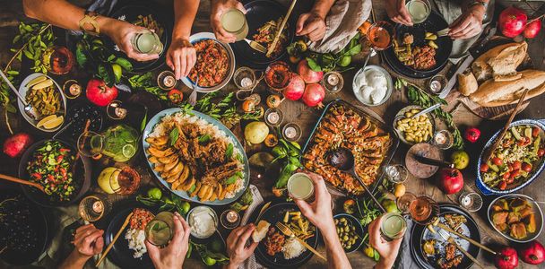 Flat-lay of family celebrating over rustic table with Turkish cuisine lamb chops, quince, green bean, vegetable salad, babaganush, rice pilav, pumpkin dessert, lemonade, top view. Middle East cuisine - Photo, image