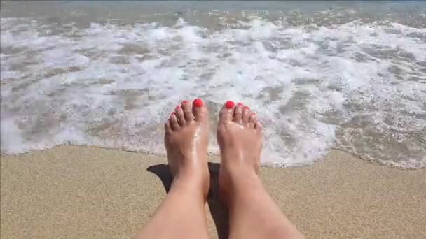 Close up de ondas do mar salpicando sobre pés femininos bronzeados - Filmagem, Vídeo