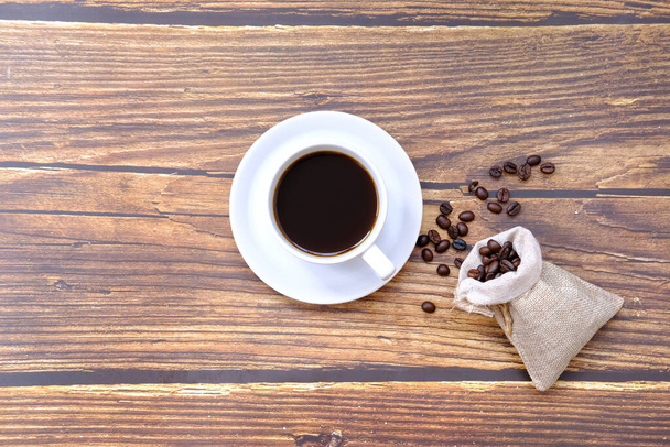 φλιτζάνι καφέ και κόκκους καφέ σε παλιό ξύλινο τραπέζι φόντο - Φωτογραφία, εικόνα