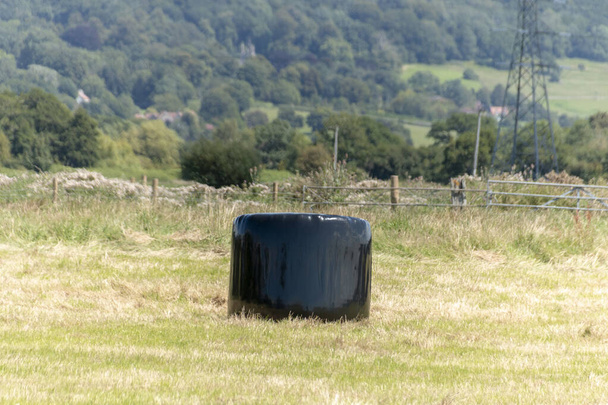 крупный план сенокосов, покрытых черным пластиком для защиты от стихии  - Фото, изображение