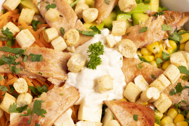 Ensalada Caesar con mucho pollo, salsa crotones de pan y maiz en un bowl blanco sobre un mantel de rayas - Foto, Imagen