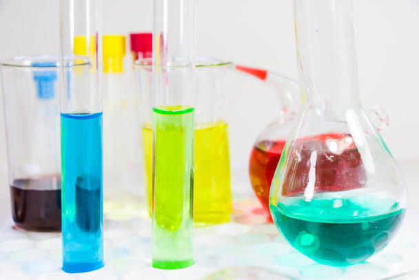 Laboratoryjne chemiczne pierwiastki ciekłe i diagnozy badawcze, przyrządy i przedmioty w sterylnej tabeli, wyroby szklane i pipety. - Zdjęcie, obraz