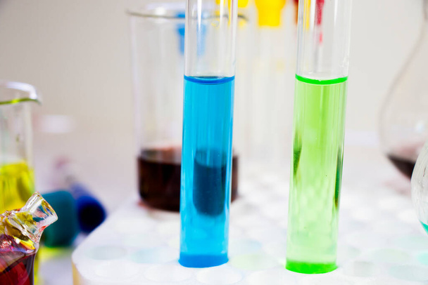 Laboratóriumi kémiai folyékony elemek és kutatási diagnosztikák, műszerek és tárgyak a steril asztalban, üvegedényekben és pipettákban. - Fotó, kép