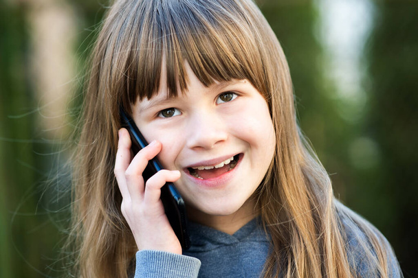 Porträt eines hübschen Mädchens mit langen Haaren, das auf dem Handy spricht. Kleine weibliche Kinder kommunizieren per Smartphone. Kommunikationskonzept für Kinder. - Foto, Bild