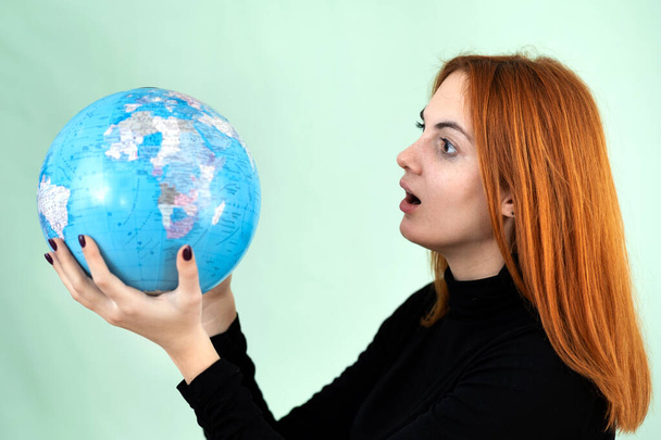 Ritratto di una giovane donna triste e preoccupata che tiene in mano il globo geografico del mondo. Destinazione di viaggio e concetto di protezione del pianeta. - Foto, immagini