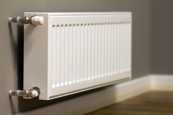 Радиатор нагрева белого металла, установленный на серой стене внутри комнаты. - Фото, изображение