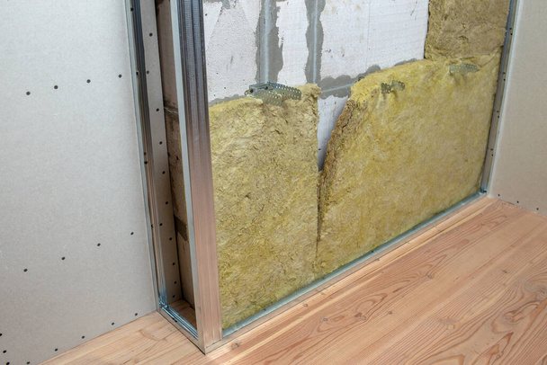 Parede de uma sala em renovação com isolamento de lã de rocha mineral e estrutura metálica preparada para placas de drywall
. - Foto, Imagem