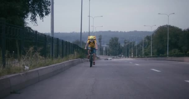 Bisikletli kurye yolda bisiklet sürüyor. - Video, Çekim